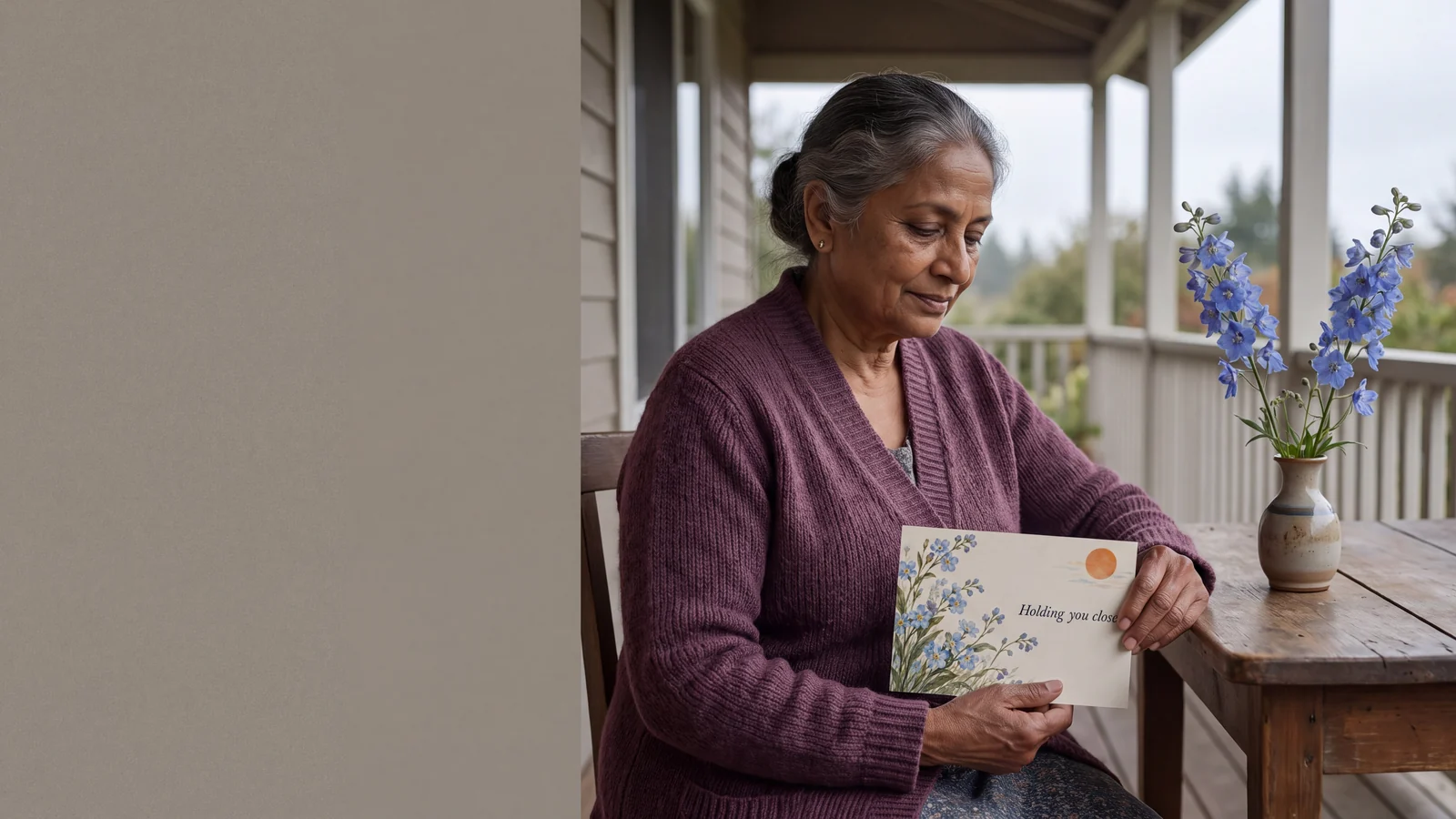 A woman quietly receives a comforting postcard beside blue flowers from her garden.