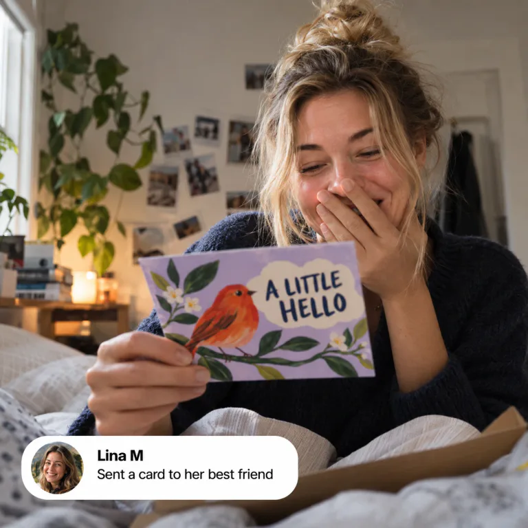 Lina hiding a smile behind her hand, reading an “A little hello” postcard